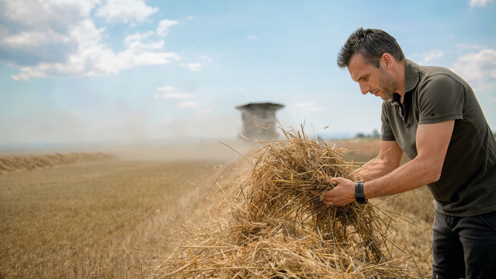 Un hombre comprueba la paja en el campo delante de la Fendt IDEAL