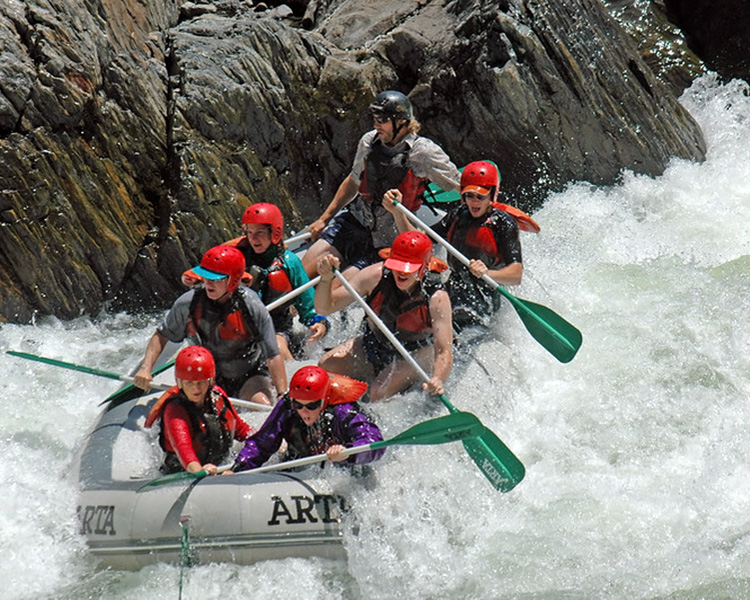 A group of people in a raft enjoying the wild whitewater rapids of the Tuolumne river.