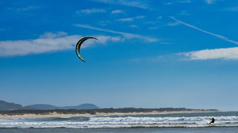 Kitesurfer in der Brandung an einem Sandstrand