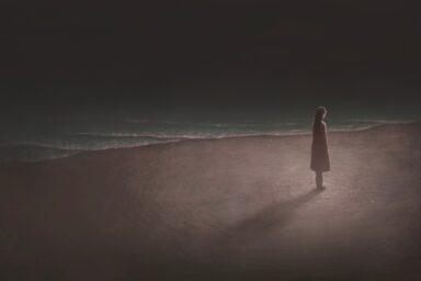 A solitary figure stands alone on a dark beach at night, waves lapping at the shore, feeling suicidal