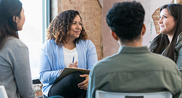 A group of people siting in a circle, learning about mental health resources.