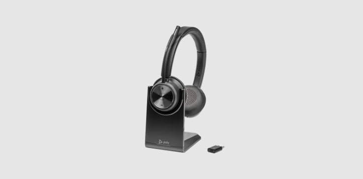 Poly Savi 7320 UC series wireless headset on desktop charging stand shown alongside USB DECT adapter