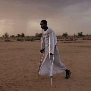 A man walks using crutches in a refugee camp