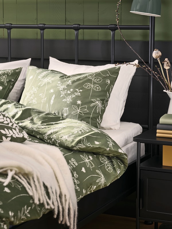 Close up of an anthracite STJÄRNÖ bed dressed with green SLÅNGULDMAL duvet cover and pillowcase.