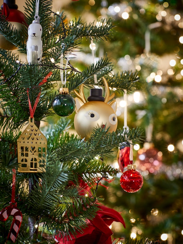 Close-up of VINTERFINT artificial tree with ornaments including colourful glass baubles, candy cane and reindeer designs.