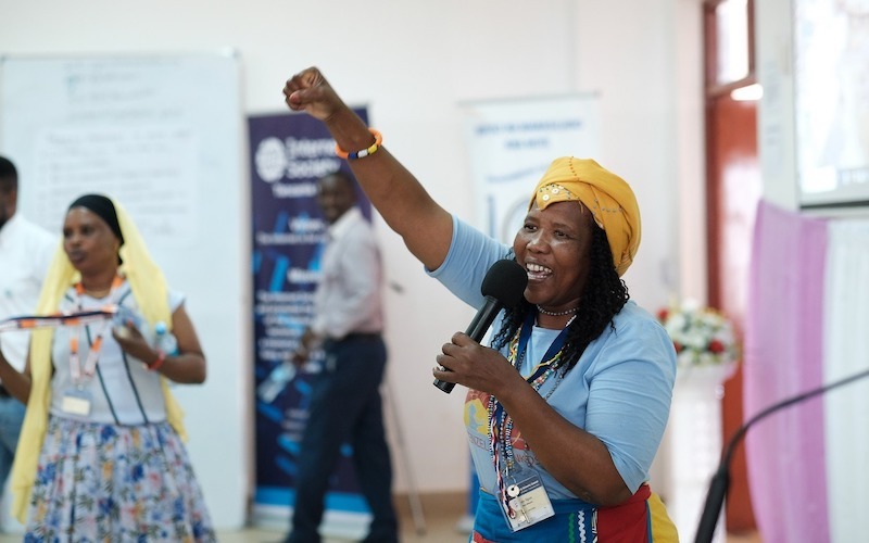 a woman holding a microphone in one hand while holding the other up with her fist clenched