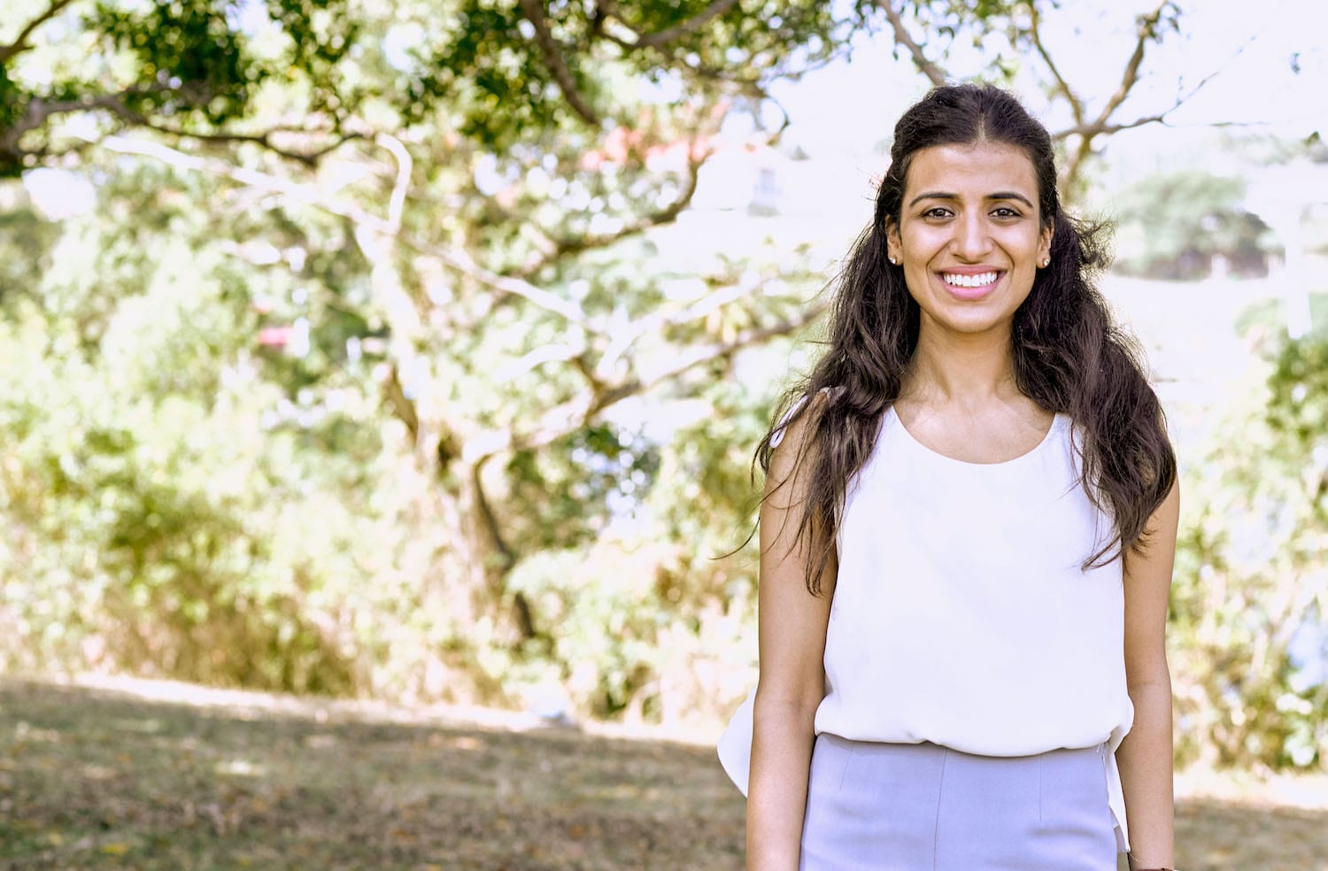 a girl with a long hair smiling while posing for a photo outdoors