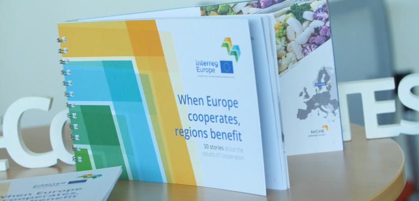 Publication entitled 'When Europe cooperates, regions benefit' placed upon a table with hashtag Europe cooperates behind it