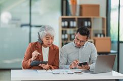 Senior business woman and young man working together analyzing finances