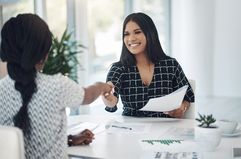 Two young businesswomen shaking hands