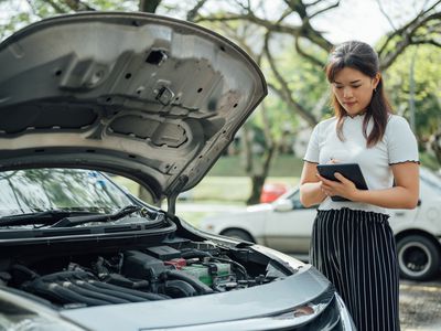 Automobile insurance adjuster uses digital tablet to inspect damage to vehicle.