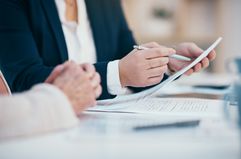 Hands working, reading and writing on business meeting notes in an office boardroom. Closeup view of corporate executive team doing work. 