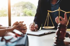 Two people looking at documents by scales of justice