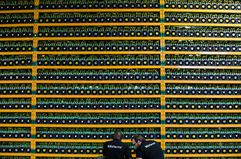 Two technicians work in a big bitcoin mining facility