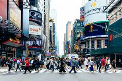 A crowd crossing at a busy crosswalk in Times Square