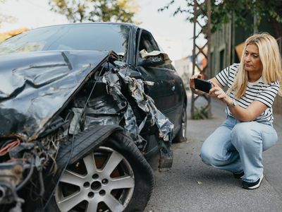 A driver takes a photo of a damaged car after an accident