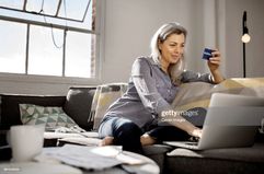 Woman Sits on Couch with Laptop and Credit Card