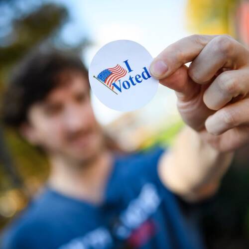 An individual holds an I Voted sticker