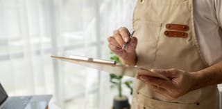 Close up of person checking off items from a clipboard 