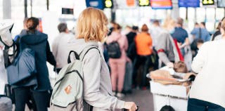 A tourist in line at an airport, waiting to get her boarding pass and check her bag