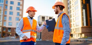 Two contractors in orange vests having a conversation about the project they are working on