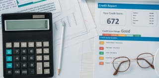 Top view of credit report, calculator, and glasses on a desk