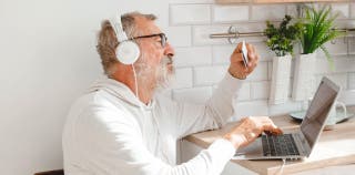 Older man using a laptop and holding a credit card to pay a bill