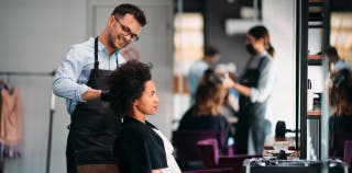 A woman getting her hair styled by a male hairdresser 