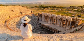 A person sitting at the top of a ancient amphitheater in Turkey.