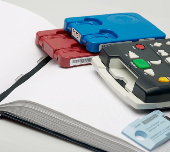 Photo of a braille book, book reader, and cartridges.