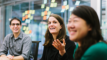 Three people in conversation in front of post-in notes