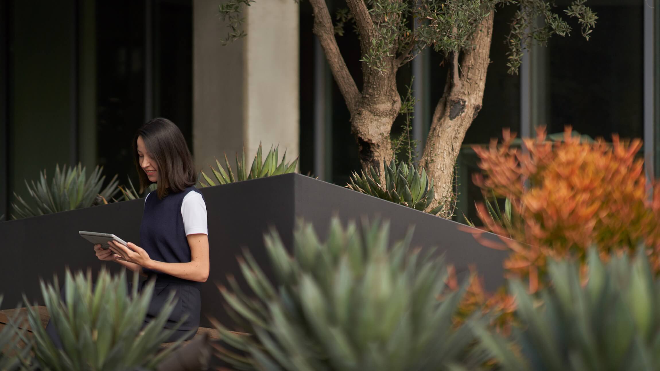 A woman sitting outside working on a tablet.