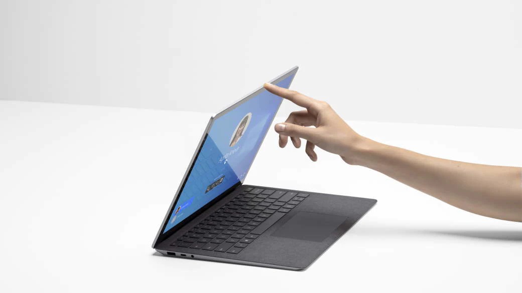 A person uses their finger to push open their laptop.