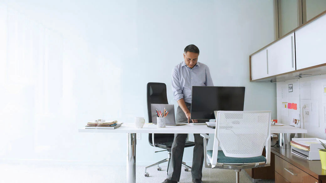 A Microsoft employee at his stand-up desk working on his computer.