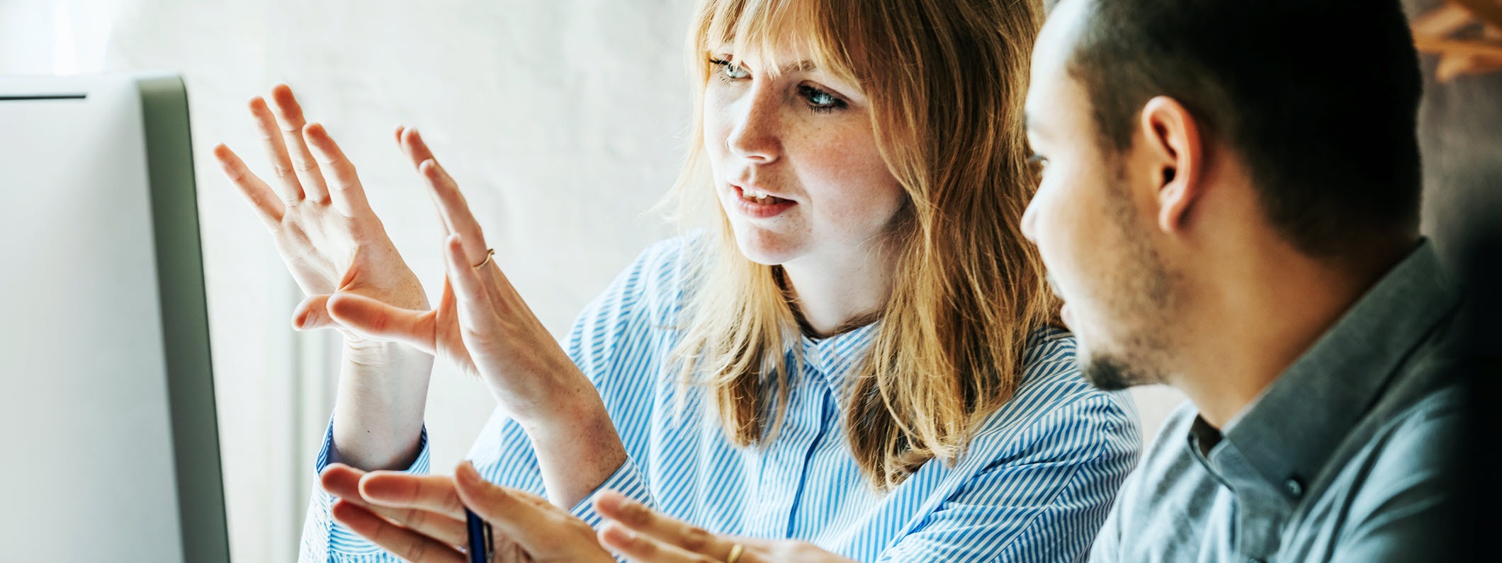 Two coworkers brainstorming in front of a computer screen.