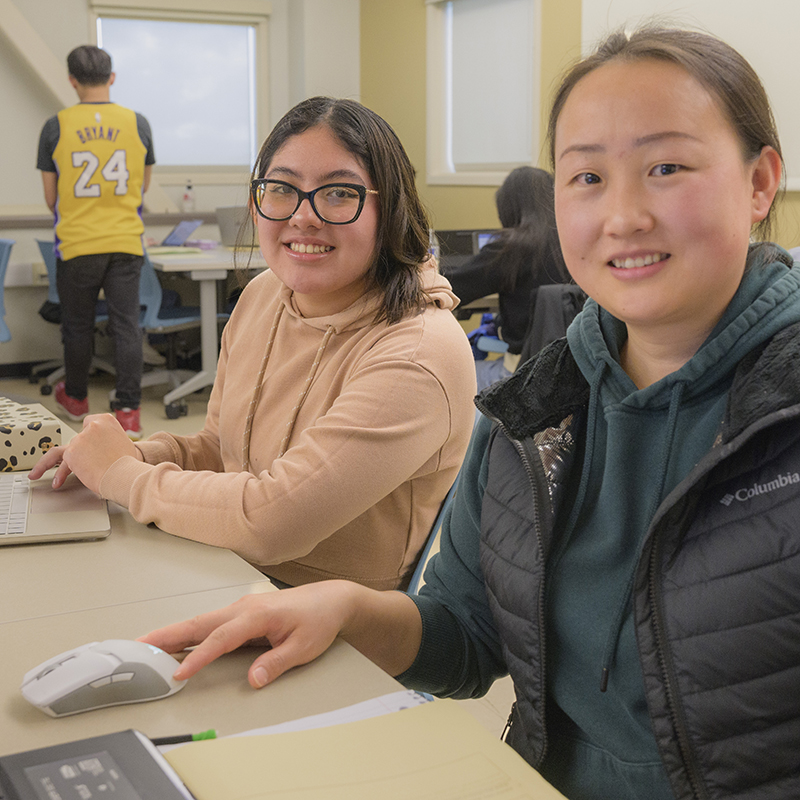 Students smile in front of their computers.