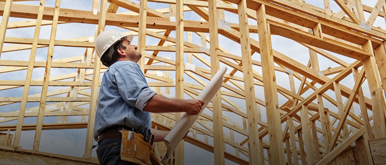 A construction worker next to a frame of a house