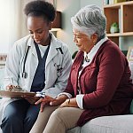 Elderly Latina woman speaking to a young Black woman doctor.