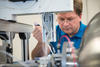 Alex Grishaev leans over a counter full of scientific equipment, looking down at his work. 