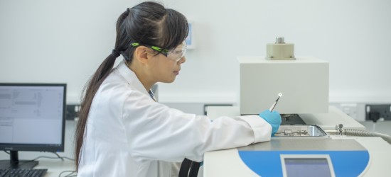 A female technician in a lab carrying out maintenance on a machine