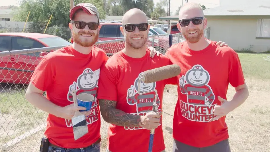 three men holding paint brushes