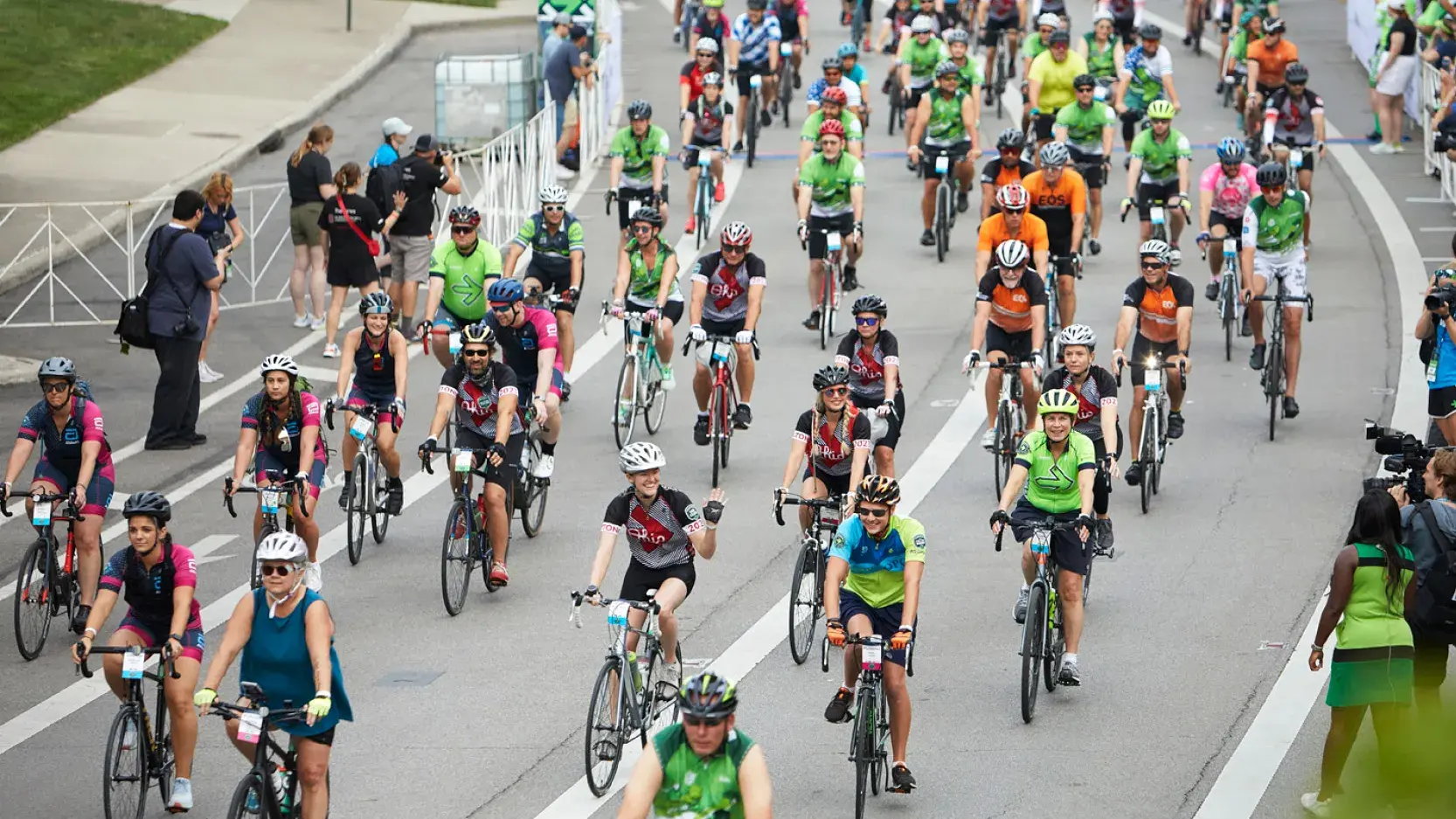 A large group of cyclists ride on a city street