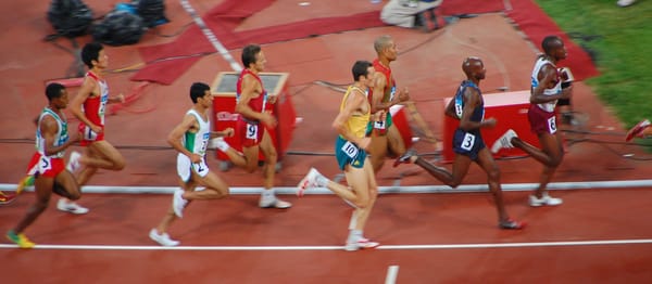 A cluster of male athletes racing on a track. 