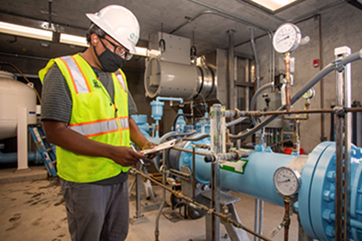 masked technician inspecting a water pump