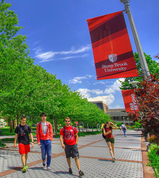 Three students walking through Stony Brook Campus on a beautiful sunny day