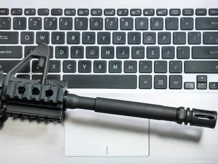 Photo of the barrel of a rifle on top of a keyboard