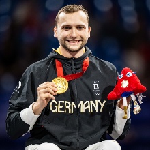 Maurice Schmidt nach der Siegerehrung mit seiner Goldmedaille und dem Paralympics-Maskottchen.