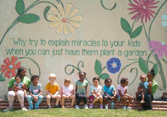 Two adults with children sitting in front of a mural