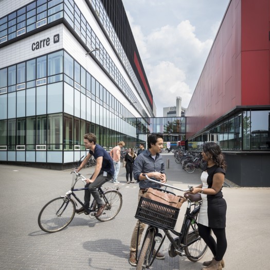 Studenten staan met hun fietsen op de campus.