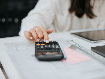 Young woman preparing home budget, using laptop and calculator